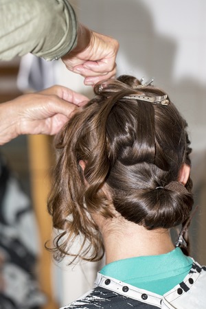 Hairdresser makes upper bun chignon wedding hairstyle close-upの写真素材