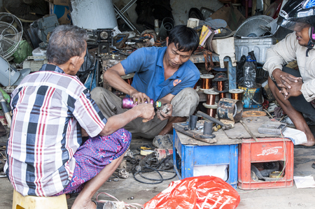 Bali, Indonesia - July 30, 2013. Unidentified men reparing motors engine on the floor, poor garage owner doing mechanicのeditorial素材