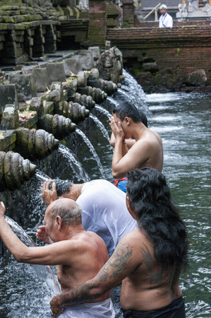 Bali, Indonesia - July 30, 2013. Holy Spring Water Tirta Empul Hindu Temple, unidentified people have a bath in the temple under the waterfalls, to be cleansed.のeditorial素材