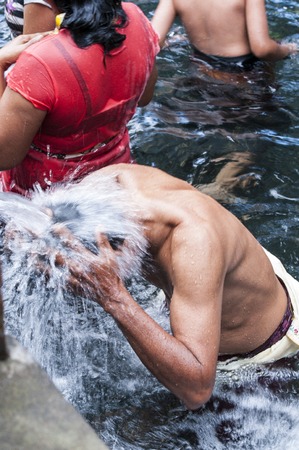 Bali, Indonesia - July 30, 2013. Holy Spring Water Tirta Empul Hindu Temple, unidentified people have a bath in the temple under the waterfalls, to be cleansed.のeditorial素材