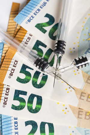 Syringes and euros banknotes bills. Cost of health, medicine, drug. Close-up.の写真素材