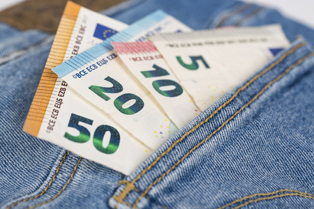 Banknotes bills cash of Euro currency sticking out of the blue denim jeans pocket. Money in jeans...