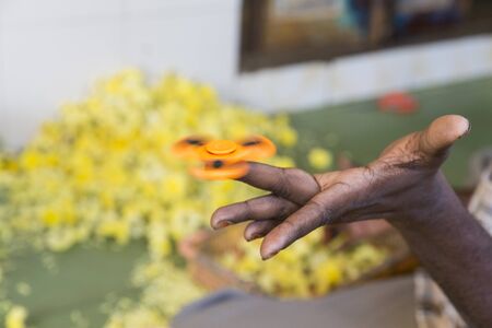 Orange hand spinner, fidgeting hand man adult indian, asian, black hand, toy
