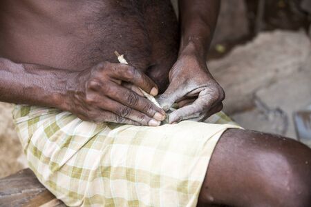 Close up of senior indian asian man sculptor carver hands working on his marble sculpture in his workshop with chisel.の写真素材