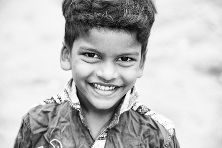 PONDICHERY, PUDUCHERRY, TAMIL NADU, INDIA - SEPTEMBER CIRCA, 2017. Portrait of unidentified Indian poor kid boy is smiling outdoor in the street. Black and whiteのeditorial素材