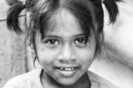 PONDICHERY, PUDUCHERRY, TAMIL NADU, INDIA - SEPTEMBER CIRCA, 2017. Portrait of unidentified Indian poor kid child girl is smiling outdoor in the street/ Black and whiteのeditorial素材