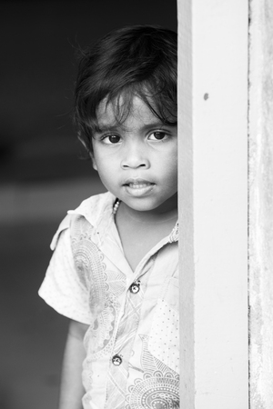 PONDICHERY, PUDUCHERRY, TAMIL NADU, INDIA - SEPTEMBER CIRCA, 2017. Portrait of unidentified Indian poor kid boy is smiling outdoor in the street. Black and whiteのeditorial素材