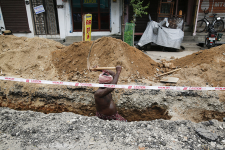 PONDICHERY, PUDUCHERY, INDIA - SEPTEMBER 04, 2017. Unidentified workers with shovels in a trench, dig trenches along the road. Concept of hard work in constructionのeditorial素材