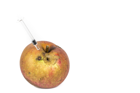 Close-up Boring trace of a codling moth Cydia Pomonella, in a wormy apple. On white background. With syringe needle. Concept non organic food and genetically modified organism. Place to writeの写真素材