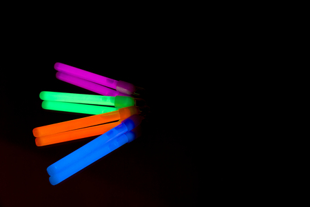 Colorful fluorescent light neon glow stick on black background.
