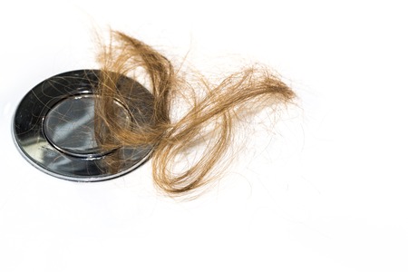 Hair loss on washbasin. Long brown hair on white basin in the bathroom. Healthcare conceptの写真素材