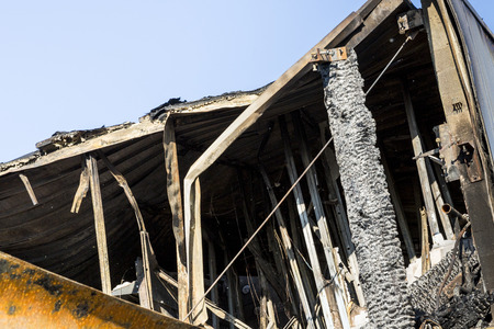 Damaged roof industry supermarket after arson fire with burn debris of twisted metal structure after...