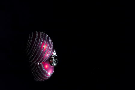 Purple christmas decorative ball ornaments on a mirror in front of a black background. Low key photography. Luxury creative design purity concept.の写真素材