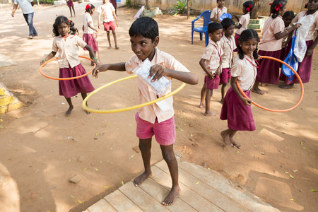 PUDUCHERY, INDIA - MARCH Circa, 2018 : Unidentified boys and girls at school playing with new games hula hoop in playground outdoor. Smiling, happy, excited, funny, excited proud faces. Emotions and feelingsのeditorial素材