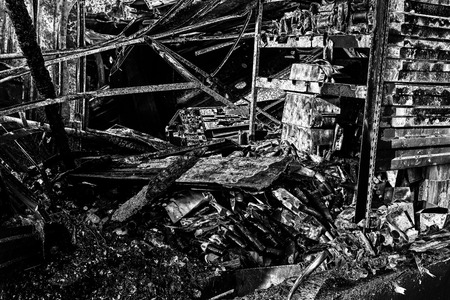 Damaged industry supermarket after arson fire with burn debris of twisted metallic wood structure...