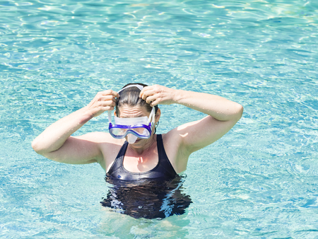 Family mother caucasian woman wearing mask swimming in the pool. Happy holiday concept. Cute happy little boy swimming and snorking in the sea ocean in crystal blue waterの写真素材