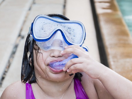 Teenager funny girl wearing mask swimming in the pool. Happy holiday concept. Cute happy little boy swimming and snorking in the sea ocean in crystal blue waterの写真素材
