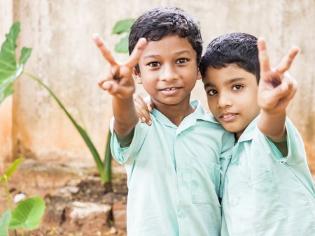 PUDUCHERRY, INDIA - DECEMBER Circa, 2018. Unidentified happy funny children friends classmates in government school uniforms smiling laughing doing victory peace sign gesture. Portrait of school teenagers enjoying friendship emotion.のeditorial素材