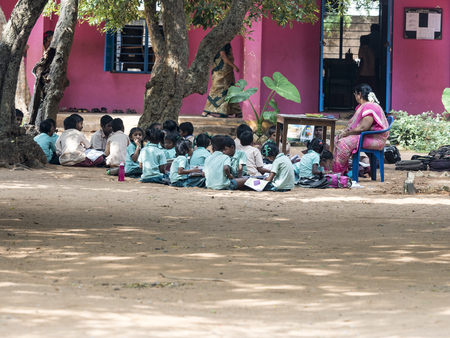PUDUCHERRY, INDIA - DECEMBER Circa, 2018. Unidentified group children girls boys friends classmates in government school uniforms sitting on floor, studying with books outdoors.のeditorial素材