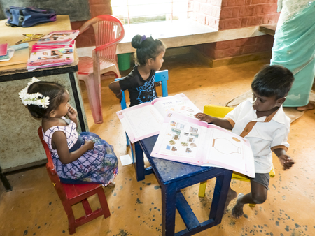 PUDUCHERY, INDIA - DECEMBER Circa, 2018. Unidentified adorable little child, boys, girls sitting in a creche, reading books. Poor conditions in government preschool.のeditorial素材