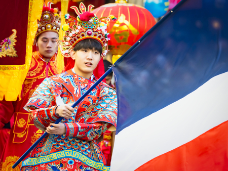 PARIS, FRANCE - FEBRUARY 17, 2019. Last day of the chinese new year celebration festival in street. Portrait of man with colorful costumes, decorations and french flag. Happy face and concentration. Year of pigのeditorial素材