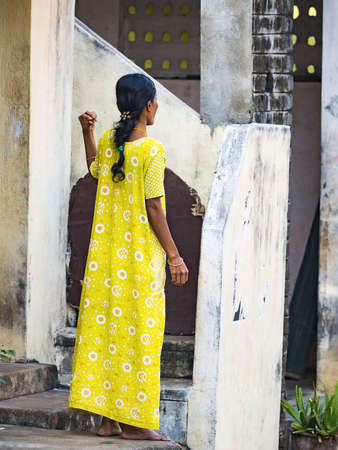 PUDUCHERY, INDIA - DECEMBER Circa, 2018. Unidentified young and elegant woman in indian yellow sari on the streets of village, India. Woman posing in traditional indian clothes. View from the back.のeditorial素材
