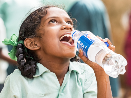 PUDUCHERY, INDIA - DECEMBER Circa, 2018. Portrait of unidentified handsome cute smiling indian girl outdoors, drinking water. Concept of joyful even if they are poor people.のeditorial素材