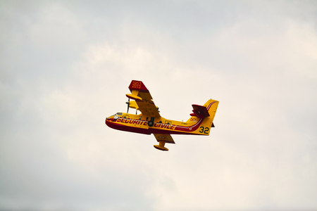 LE BOURGET, FRANCE - JUNE 24, 2017. Small yellow red seaplane hydroplane flying in the sky with clouds at International aeronautical and spatial meeting nearParisのeditorial素材