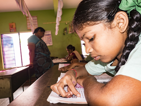 PUDUCHERRY, INDIA - DECEMBER Circa, 2018. Unidentified concentrated serious classmates in government school uniforms sitting on chair, studying reading books indoors classroom. Portrait of school teenagersのeditorial素材