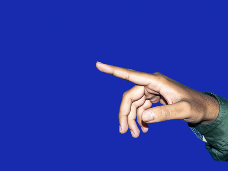 Close up of a young indian man hand pointing finger as touching screen, isolated on blue background. Innovation technology internet business concept background for graphic designerの写真素材