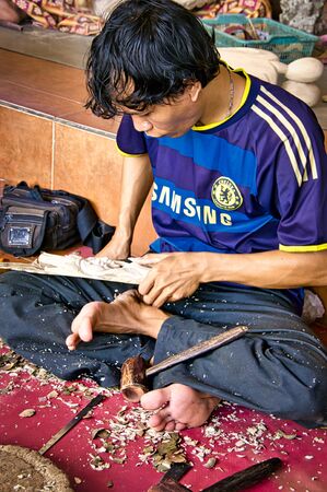 BALI, INDONESIA - FEBRUARY Circa, 2019. Unidentified Indonesian man carpenter cabinet worker working with a chisel in his workshop, sitting on the floor. Very accurate manual work.のeditorial素材