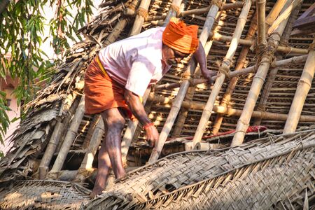 PUDUCHERRY, TAMIL NADU - DECEMBER Circa, 2018. Unidentified Indian workers covered the top of the log cabin with coconut leaves to serve tourists. Hard job for Dalit peopleのeditorial素材