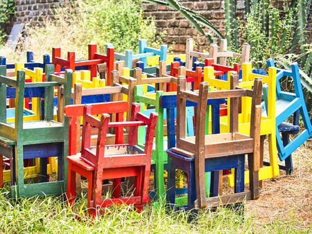 Stack of assorted colorful wooden chairs in random disarray, for children at schoolの写真素材