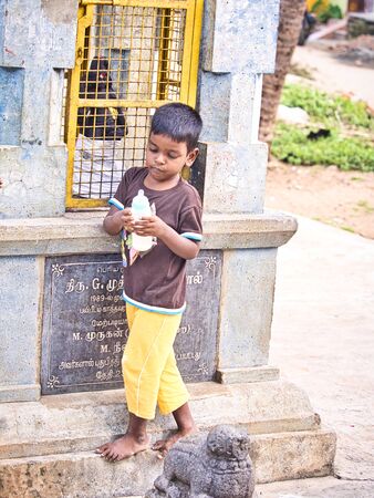 PUDUCHERRY, INDIA - DECEMBER Circa, 2018. Unidentified Shy young indian dalit boy alone in the street of village, drinking baby bottle with sad and shy expressionのeditorial素材
