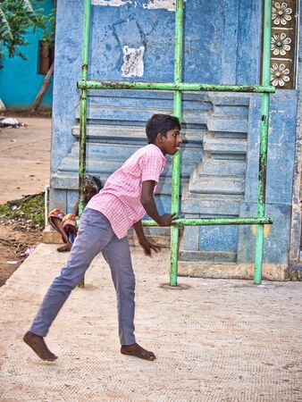 PUDUCHERRY, INDIA- DECEMBER Circa, 2018. Unidentified young boy teenager playing baseball in the street of the village in India. Baseball is considered has the national sport.のeditorial素材