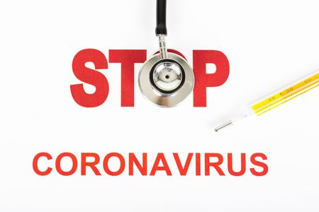 Novel Covid-19, virus concept. Text phrase Coronavirus with red letters with STOP sign on white background. Copy space. With stethoscope and thermometerの写真素材