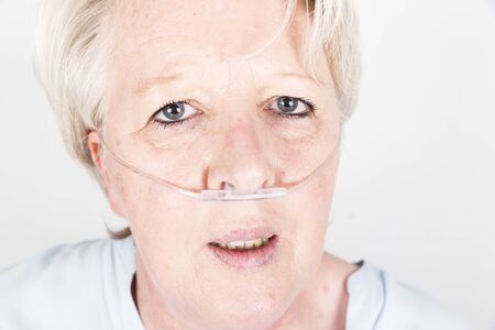 Mature caucasian european woman with blond hair and anxious behaviour, wearing an oxygene tube in...