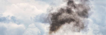 Huge plume of black smoke from fire rising high above flat land against cloud sky. Panoramic size
