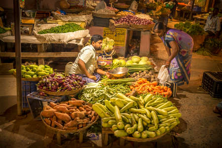 PUDUCHERRY, INDIA - March Circa, 2019. Unidentified street market vendor selling vegetables at night time. Quiet atmosphere and warm colors lights.のeditorial素材