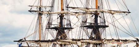 Vintage sailing ship mast ropes and tackle, Tall ship rigging mast detail, blue sky background