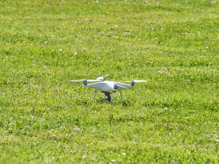 White quadrocopter flying under grass, close-up. New unmanned aerial copter. Electronics innovation.Aeromodelling. Modern Technologies.のeditorial素材