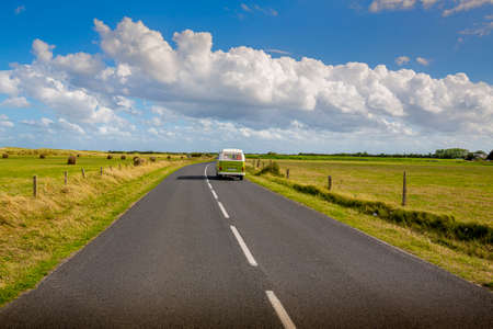 BARFLEUR, FRANCE - SEPTEMBER Circa, 2020. Road in the middle of natural country landscape with a van on the long road with blue cloudy sky background. Travel liberty conceptのeditorial素材