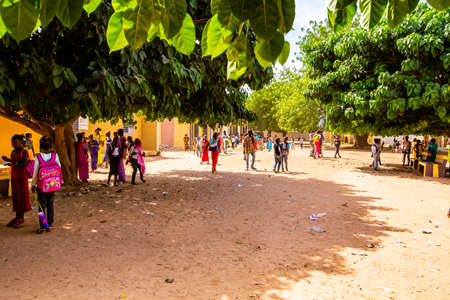MBOUR, SENEGAL - DECEMBER Circa, 2020. Unidentified young African school children walking in the playground at end of classroom. With colorful clothes. Life in rural and poor villageのeditorial素材