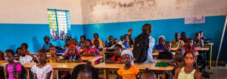 MBOUR, SENEGAL - DECEMBER Circa, 2020. Unidentified serious and sad african children sitting at desks in a classroom in a primary school. New class with new desks, roof, paintings. Due to international NGO help.のeditorial素材