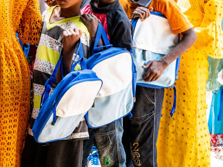 MBOUR, SENEGAL - DECEMBER Circa, 2020. Group of unidentified teenagers standing up in playground of the school, outdoors on a sunny summer day. Happy to get new bags given by international ngo. Poor rural children.のeditorial素材