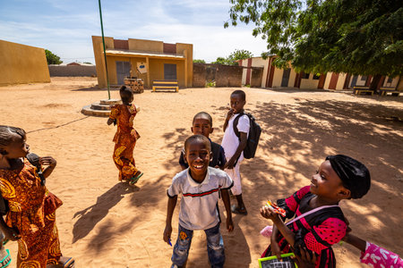 MBOUR, SENEGAL - DECEMBER Circa, 2020. Group of unidentified teenagers standing up in playground of the school, outdoors on a sunny summer day. Happy to get new bags given by international ngo. Poor rural children.のeditorial素材
