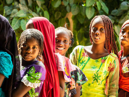 MBOUR, SENEGAL - DECEMBER Circa, 2020. Group of unidentified teenagers standing up in playground of the school, outdoors on a sunny summer day. Waiting for new bags given by international ngo. Poor rural children.のeditorial素材