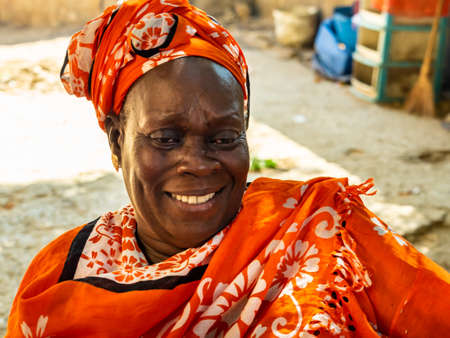 MBOUR, SENEGAL - JANUARY Circa, 2021. Unidentified senegalese pretty mature woman in traditional dress outdoor looking up smiling. Poverty and happiness in villageのeditorial素材