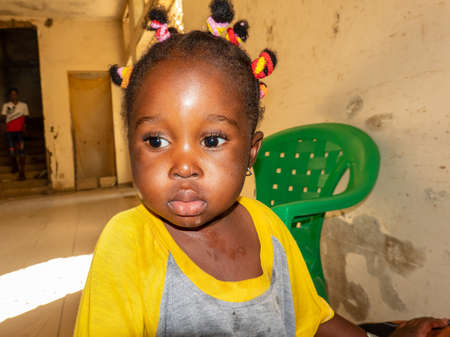 MBOUR, SENEGAL - JANUARY Circa, 2021. Unidentified child girl baby with sad anxious face, thinking about way of life in poor african village.のeditorial素材
