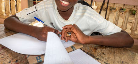 MBOUR, SENEGAL - DECEMBER Circa, 2021. Unidentified young child writing letter to godfather or...